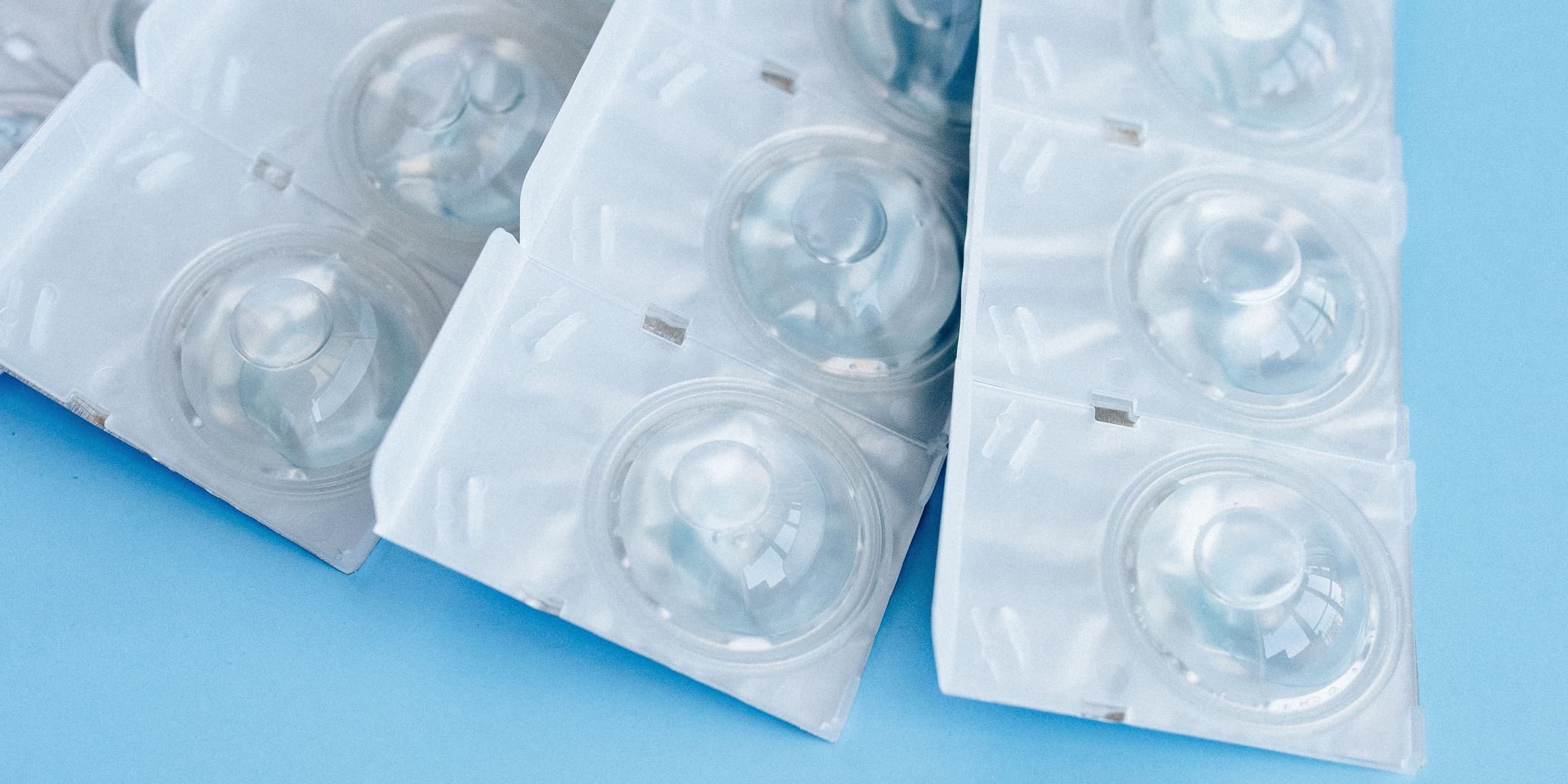 Disposable contact lenses and tweezers on a blue background